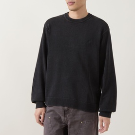 Model wearing Carhartt Kori Logo Knit Sweater in Black, crew neck, long sleeves, tonal chest logo, frayed details, styled with grey jeans.