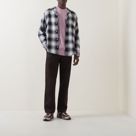 Model wearing Carhartt Cubist Logo T-Shirt in Hortensia pink, styled with grey check overshirt and dark brown trousers.