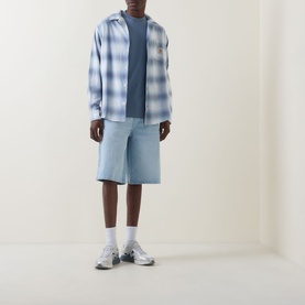 Model wearing Carhartt Formidable Logo T-Shirt in Shady Blue, styled with light blue check shirt, matching shorts and grey trainers.