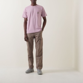 Model wearing Carhartt Pocket Logo T-Shirt in Hortensia pink with chest patch pocket, styled with taupe cargo trousers and grey trainers.