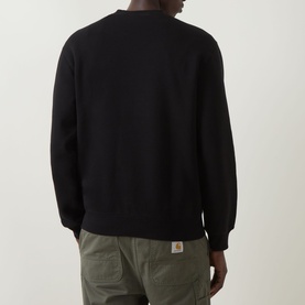 Model wearing Carhartt Pinball Logo Sweatshirt in Black, rear view, with olive cargo trousers. Crew neck, dropped shoulders, ribbed trims.