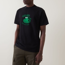 Model wearing Carhartt Please Don't Snitch Logo T-Shirt in black, with green graphic print on chest, styled with khaki cargo trousers.