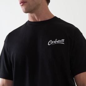 Model wearing Carhartt Pup Logo T-Shirt in black, showing contrast script logo graphic on chest. Crew neck, short sleeves, midweight cotton.