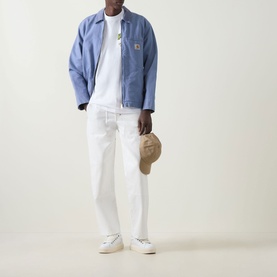 Model wearing Carhartt Pinball Logo T-Shirt in White, styled with a blue jacket, white trousers, a cap and white trainers.
