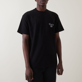 Model wearing Carhartt Gracious Logo T-Shirt in black with crew neckline, dropped shoulders, and chest logo embroidery