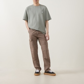Model wearing Carhartt Madison Logo T-Shirt in Shady Green with white embroidered logo, styled with brown cargo trousers and trainers.