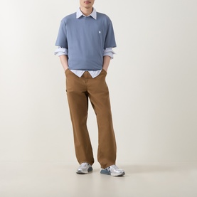 Model wearing Carhartt Crew Neck T in Shady Blue, styled with a white shirt, tan trousers, and grey trainers.