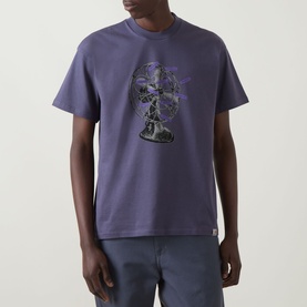 Model wearing Carhartt Fan Graphic Logo T-Shirt in Shady Purple with fan graphic print, crew neck, short sleeves, paired with light trousers.