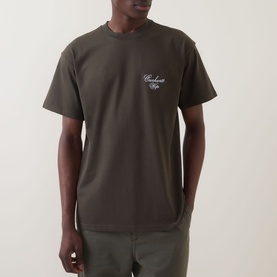 Model wearing Carhartt Gracious Logo T-Shirt in Cypress, crew neck, short sleeves, with embroidered chest logo, styled with olive trousers.