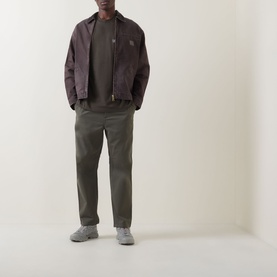 Model wearing Carhartt Gracious Logo T-Shirt in Cypress, styled with dark brown overshirt and olive trousers with grey trainers.
