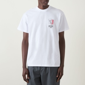 Model wearing Carhartt Playing Cards Logo T-Shirt in white, crew neck with small chest graphic, styled with grey striped trousers.