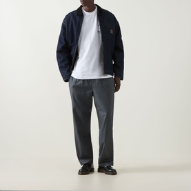 Model wearing Carhartt Playing Cards Logo T-Shirt in white with navy zip jacket, grey trousers and dark loafers.