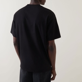 Model wearing Carhartt Madison Logo T-Shirt in black, rear view, short sleeves, relaxed fit, styled with dark jeans.