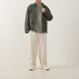 Model wearing Carhartt Stacked Grapes Logo T-Shirt in Shady Green, styled with olive overshirt, cream wide-leg trousers and white trainers.