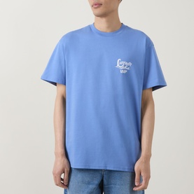 Model wearing Carhartt Waves Logo T-Shirt in Curacao blue, with white chest graphic, crew neck and short sleeves, styled with light wash jeans.
