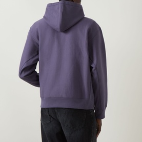 Model wearing Carhartt American Script Logo Hoodie in Shady Purple, back view, with black jeans. Dropped shoulders, ribbed hem, adjustable drawstring