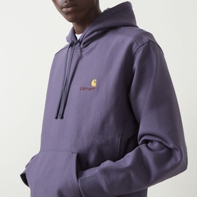 Model wearing Carhartt American Script Logo Hoodie in Shady Purple with embroidered chest logo, drawstring hood, and kangaroo pocket.