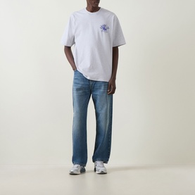 Model wearing Carhartt Built Different Logo T-Shirt in Ash Heather, styled with mid-blue straight-leg jeans and grey trainers.
