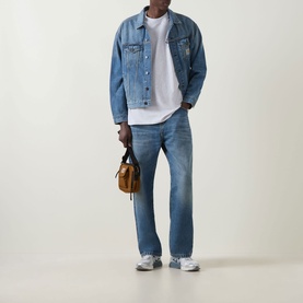 Model wearing Carhartt Built Different Logo T-Shirt in Ash Heather, styled with denim jacket, jeans, and grey trainers, carrying tan bag.