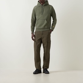 Model wearing Carhartt Chase Logo Hoodie in Leaf/Gold with olive cargo trousers and black trainers.