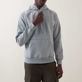 Model wearing Carhartt Chase Logo Hoodie in grey heather, with kangaroo pocket and gold embroidered sleeve logo, styled with khaki cargo trousers.
