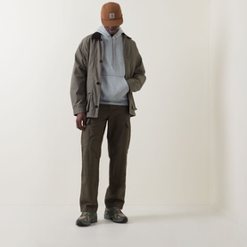 Model wearing Carhartt Chase Logo Hoodie in Grey Heather/Gold, styled with olive jacket, brown cargo trousers, tan beanie and grey trainers.