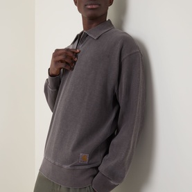Model wearing Carhartt Harper Heavyweight Polo Shirt in Tobacco, featuring flat collar and long sleeves, styled with olive trousers.