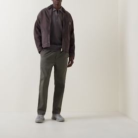 Model wearing Carhartt Harper Heavyweight Polo Shirt in Tobacco, styled with dark olive trousers and a brown jacket.