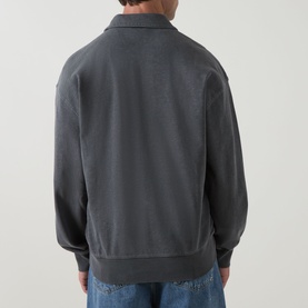 Model wearing Carhartt Harper Logo Half-Zip Sweatshirt in Black, shown from behind with polo collar and ribbed hem, styled with blue jeans.