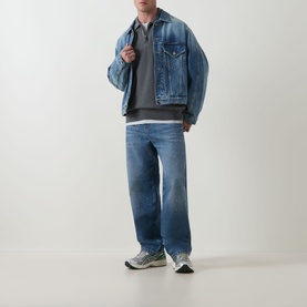 Model wearing Carhartt Harper Logo Half-Zip Sweatshirt in Black, styled with blue denim jacket, wide-leg jeans and grey trainers.