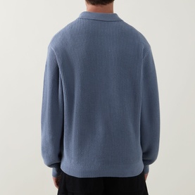 Model wearing Carhartt Shady Blue cotton knit polo, rear view showing ribbed texture and relaxed fit with open collar