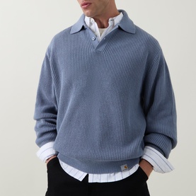 Model wearing Carhartt Shady Blue cotton ribbed polo knit, styled over a white collared shirt with black trousers.