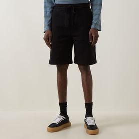 Model wearing Carhartt black cotton shorts with drawstring waist, styled with blue shirt and platform trainers