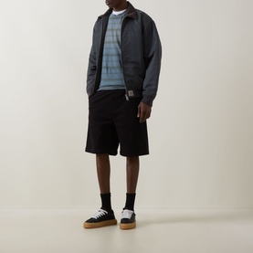 Model wearing Carhartt black cotton shorts with a striped sweatshirt, zip jacket, and gum-sole trainers.