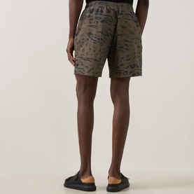 Model wearing Carhartt shorts in Duck Feather camo print, shown from rear. Styled with black slides.
