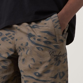 Model wearing Carhartt shorts in Duck Feather camo print with script logo detail, hand in pocket, styled with black T-shirt.