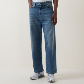 Model wearing Carhartt Landon Tapered Leg Jeans in blue, loose tapered fit with destroyed wash, styled with grey trainers