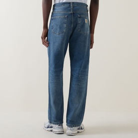 Model wearing Carhartt Landon Tapered Leg Jeans in blue, loose tapered fit, destroyed wash, five-pocket style, woven logo badge visible