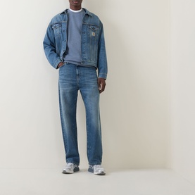 Model wearing Carhartt Landon Tapered Leg Jeans in blue with matching denim jacket and grey trainers