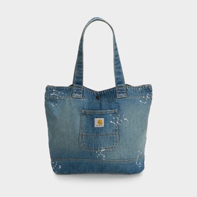 Carhartt blue denim tote bag with paint splatter detailing, front patch pocket, gold logo badge, and twin carry handles