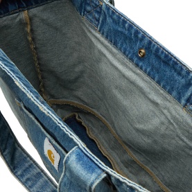 Carhartt denim tote bag in blue, interior view showing grey lining, raw-edge detail and gold logo patch on exterior