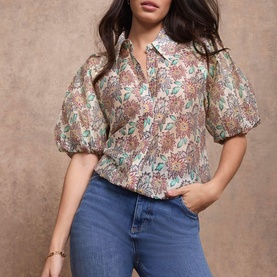 Model wearing Mint Velvet red floral puff-sleeve shirt with collar, styled with blue straight-leg jeans