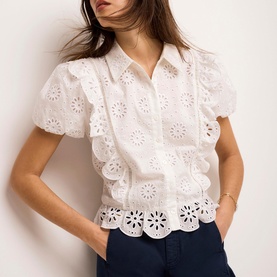 Model wearing Mint Velvet white broderie anglaise short sleeve blouse with scalloped hem, styled with navy trousers