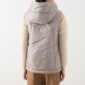 Model wearing Max Mara Cube Greengo Padded Gilet in beige, satin finish, hooded, styled with cream knit sleeves and tan trousers. Back view.