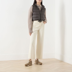 Model wearing Max Mara Cube kaki quilted down gilet with cream wide-leg trousers, grey knit top, and tan trainers.