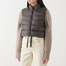 Model wearing Max Mara Cube kaki quilted gilet with zip fastening, styled with beige knit sleeves and cream trousers.