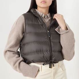 Model wearing Max Mara Cube kaki quilted polyester gilet, styled with a beige knit sweater and cream trousers.