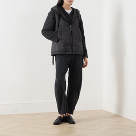 Model wearing Max Mara Cube black quilted gilet with hood, styled with black tapered trousers and black loafers.