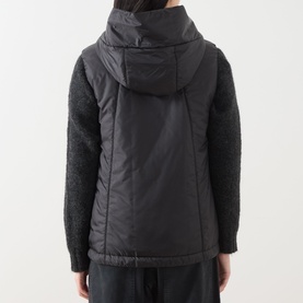Model wearing Max Mara Cube black quilted gilet with hood, shown from behind, styled with matching black textured knit sleeves and trousers