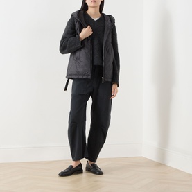 Model wearing Max Mara Cube black quilted gilet, styled with black wide-leg trousers, hoodie, and black loafers.
